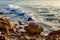 Wave breaking on rocks at shoreline at sunrise