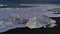 Wave breaking on small icebergs on diamond beach with black sand in southern Iceland at the ocean.