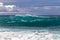 Wave breaking on western Kona coast in Hawaii. White spray and foam on the water. Rocks in foreground.