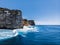 A wave breaks on the rocks of the coast of the Bukit Peninsula in Bali. The sheer cliffs of the southern coast of Bali are washed