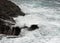 A wave breaks in stormy weather on a rocky coast