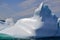 Wave crashing against large iceberg marooned near the coast