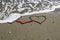 Wave erasing heart drawings on sea beach