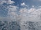 Wave explodes into the air with blue cloud sky in the background