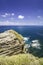 Wave hitting the rock and stunning rock island with blue sky background.