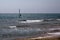 Wave Rider Windsurfing in the Ocean. Blue Water and Clear Sky. Sideview Far Shot of Surfer Balancing on Surfing Board