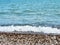 A wave rolls over the pebbled shore