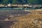 A wave runs over the pebbly beach of the resort town. Sea foam, pebbles. In the background, mountains covered with