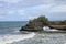 Waves arrive at a rock cliff below Batu Bolong Temple. Tanah Lot temple. Huge hole in rock cliff below Pura Batu Bolong temple.