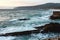 Waves on the beach, stones and a mountain in the background