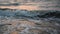 Waves beating on sand at sunset