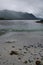 Waves break on beach as rain squall hits mountains in distance