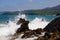 waves breaking onto rocks with a blue ocean behind them