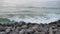 Waves breaking over rocks on the beach.