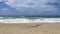 Waves breaking on shore of sandy beach in Povoa de Varzim, Portugal. Bright sunny day with blue sky and white clouds