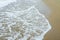 Waves breaking on shore of the sea. closeup of sea foam on wet sand