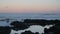 Waves Crash Over Rocks at Sunrise