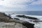 Waves crash on a rocky coast under a partly cloudy sky, capturing nature s serene and rugged beauty