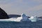 Waves crashing against icebergs stranded next to rugged coastline in bay outside St. John\\\'s