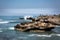 Waves crashing against a rock with a blue sky and clear blue ocean in Bali, Indonesia, Asia