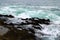 Waves crashing against the rocks at the beach on a cloudy day at Crescent Bay Beach