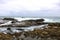 Waves crashing against the rocks at the beach on a cloudy day at Crescent Bay Beach