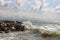 Waves crashing against rocks. Light storm. Seascape. Cloudy sky