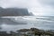 Waves are crashing ashore on Stokksnes peninsula black beach with vestrahorn mountain chain in the background.