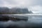 Waves are crashing ashore on Stokksnes peninsula black beach with vestrahorn mountain chain in the background