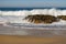 Waves crashing on rocks on Atlantic Ocean beach. Scenic seascape. Beautiful surf at seaside. Splashing waves with foam.