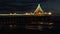 Waves crashing to the shore under a pier decorated in Christmas lights