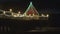 Waves crashing to the shore under a pier decorated in Christmas lights