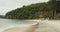 Waves crashing on tropical beach with beach restaurant. Beautiful tropical beach under a cliff with stunning blue sea