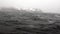 Waves and fog on background of snow rock in ocean of Antarctica.