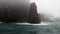 Waves and fog on background of snow rock in ocean of Antarctica.