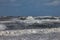 Waves of the north sea with white spindrift in front of a blue sky