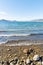 Waves on rocky shoreline of Okanagan Lake with view of blue sky and distant mountains