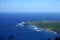 Waves roll towards Kalaupapa Peninsula with airport and Lighthouse