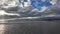 waves rolling onto a sandy beach against a blue sky with dramatic thunderclouds, sunset, beautiful landscape, slow motion