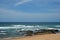 WAVES ROLLING OVER ROCKS ONTO BEACH