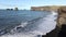 Waves run onto the beach. White foam from the waves on the background of a black beach. Surf on the ocean