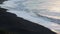 Waves run onto the beach. White foam from the waves on the background of a black beach. Surf on the ocean