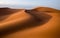Waves of sand dunes in the Sahara desert at sunset