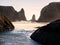 Waves on sandy beach with rock stacks