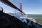 Waves splash up nearby on cliffs under Golden Gate Bridge