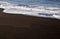 Waves spread on black sand beach