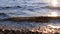 Waves and stones on the beach lit by sunlight. Beautiful sunset on the Mediterranean sea