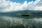 Waves on the surface of the lake water. Buildings on the shore. In the distance, the mountains are lost in the fog.