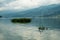 Waves on the surface of the lake water. Buildings on the shore. In the distance, the mountains are lost in the fog.