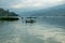 Waves on the surface of the lake water. Buildings on the shore. In the distance, the mountains are lost in the fog.